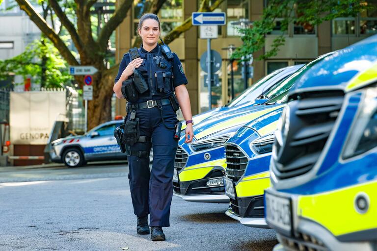 Porträt Julia Filthuth in Uniform vor Reihe Polizeifahrzeugenellvertretende Vorsitzende der Hauptjugend- und Auszubildendenvertretung