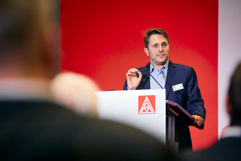 Mann spricht an Pult