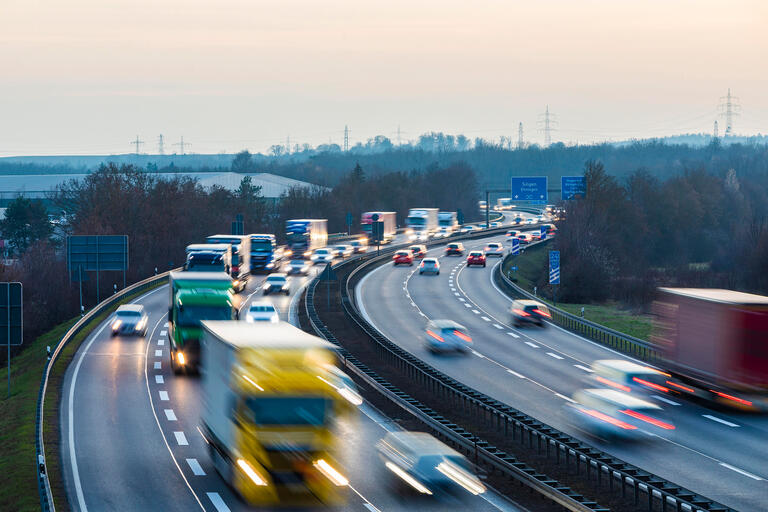 Eine Autobahn in Deutschland auf der Autos und LKWs fahren. Dien Ansicht ist verschwommen.