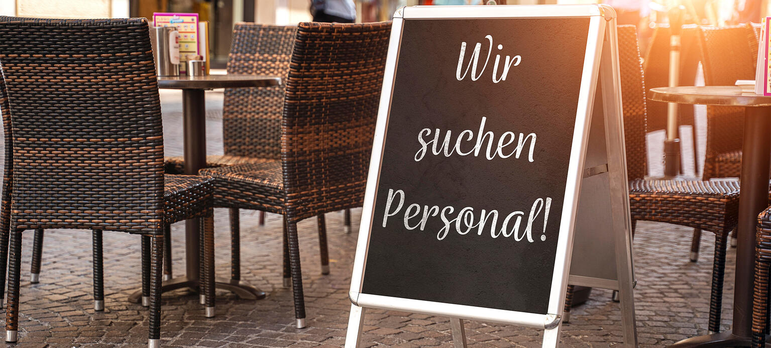 Schild vor einem Restaurant mit der Aufschrift: Wir suchen Personal. PM Gastgewerbe 