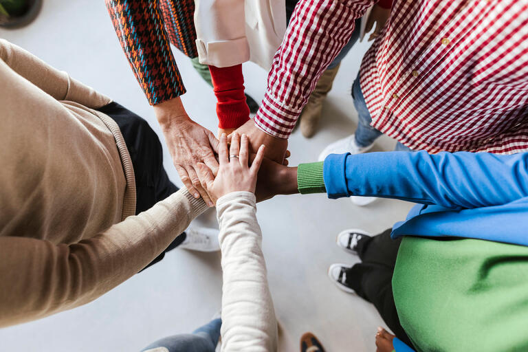 Diverse Hände liegen aufeinander.