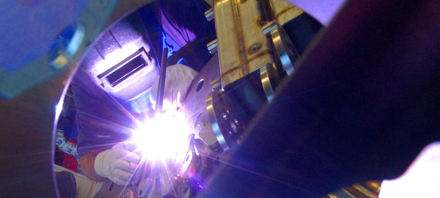 Ein Schweißer montiert Edelstahlteile.