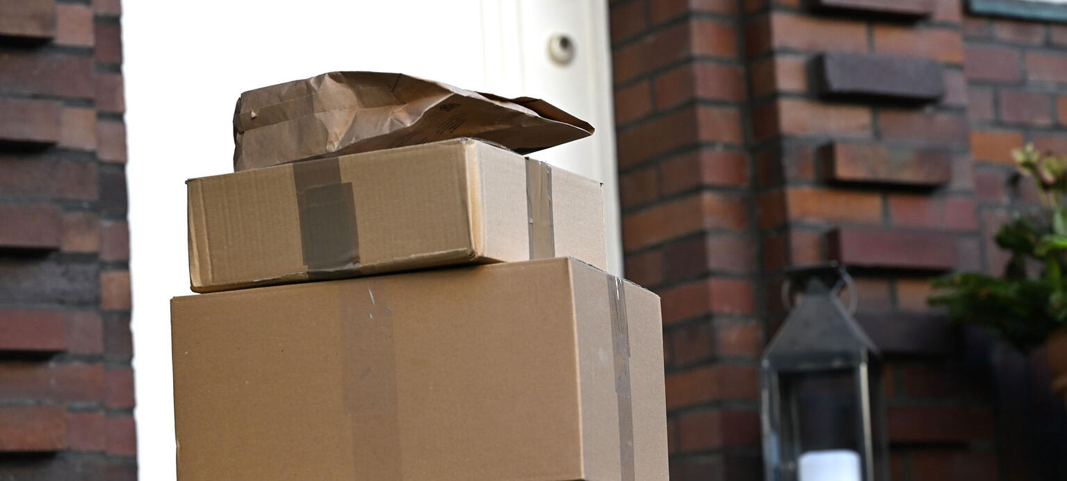 Drei Pakete liegen am Ende einer Treppe vor einer Haustür (gestellte Szene).
