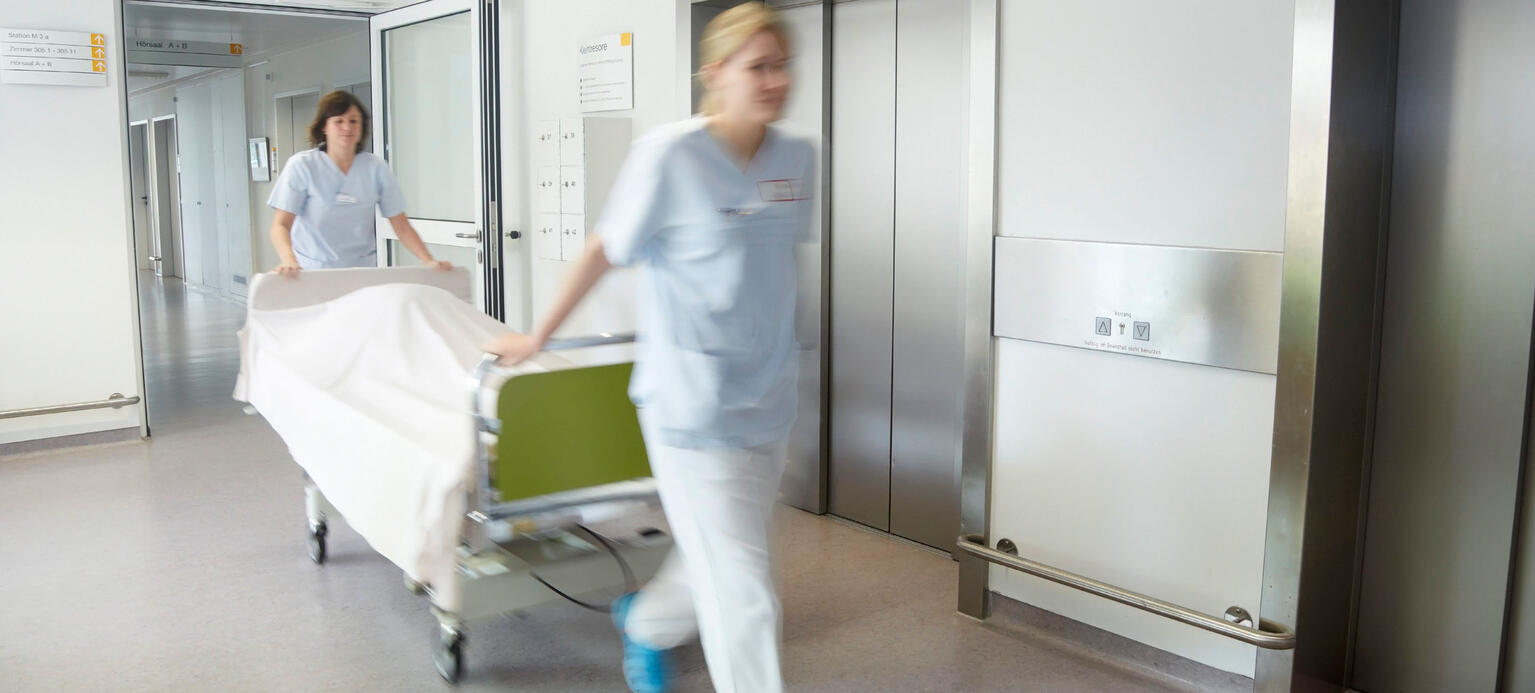Germany, Freiburg, Nurses moving hospital bed 