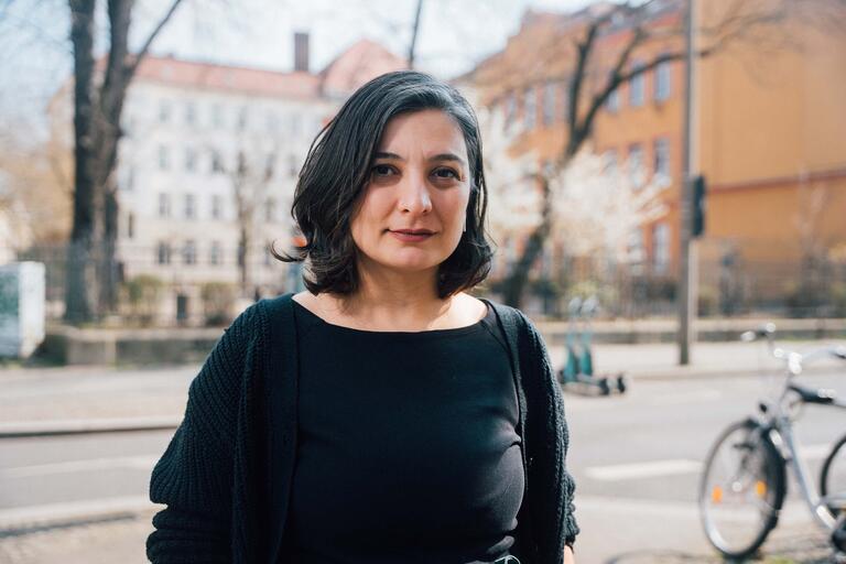 Porträt der Lehrerin Begüm Janowski mit Schulgebäude im Hintergrund