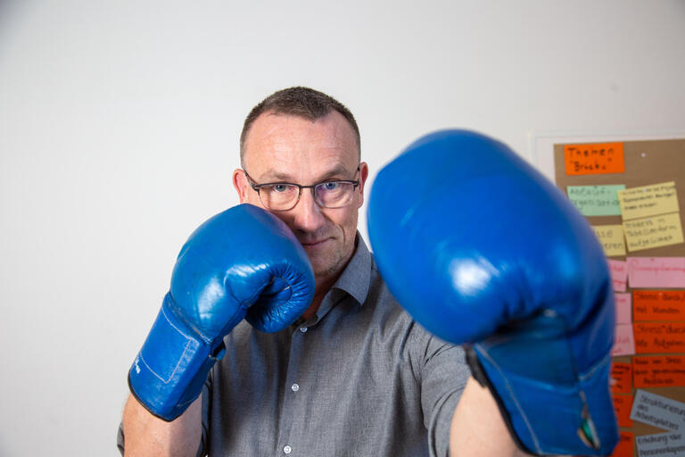 Soziologie-Professor Jonas Grutzpalk mit blauen Boxhandschuhen