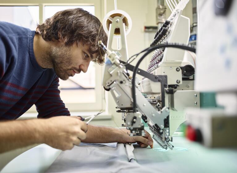 Ein Mann steht an einer Stickmaschine