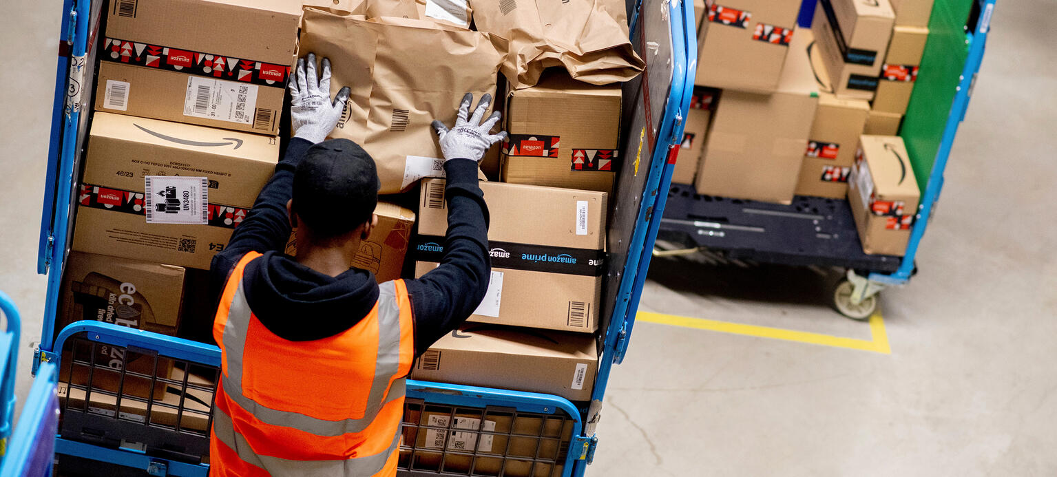 Mitarbeiter im Logistikzentrum von Amazon beim Verladen von Paketen
