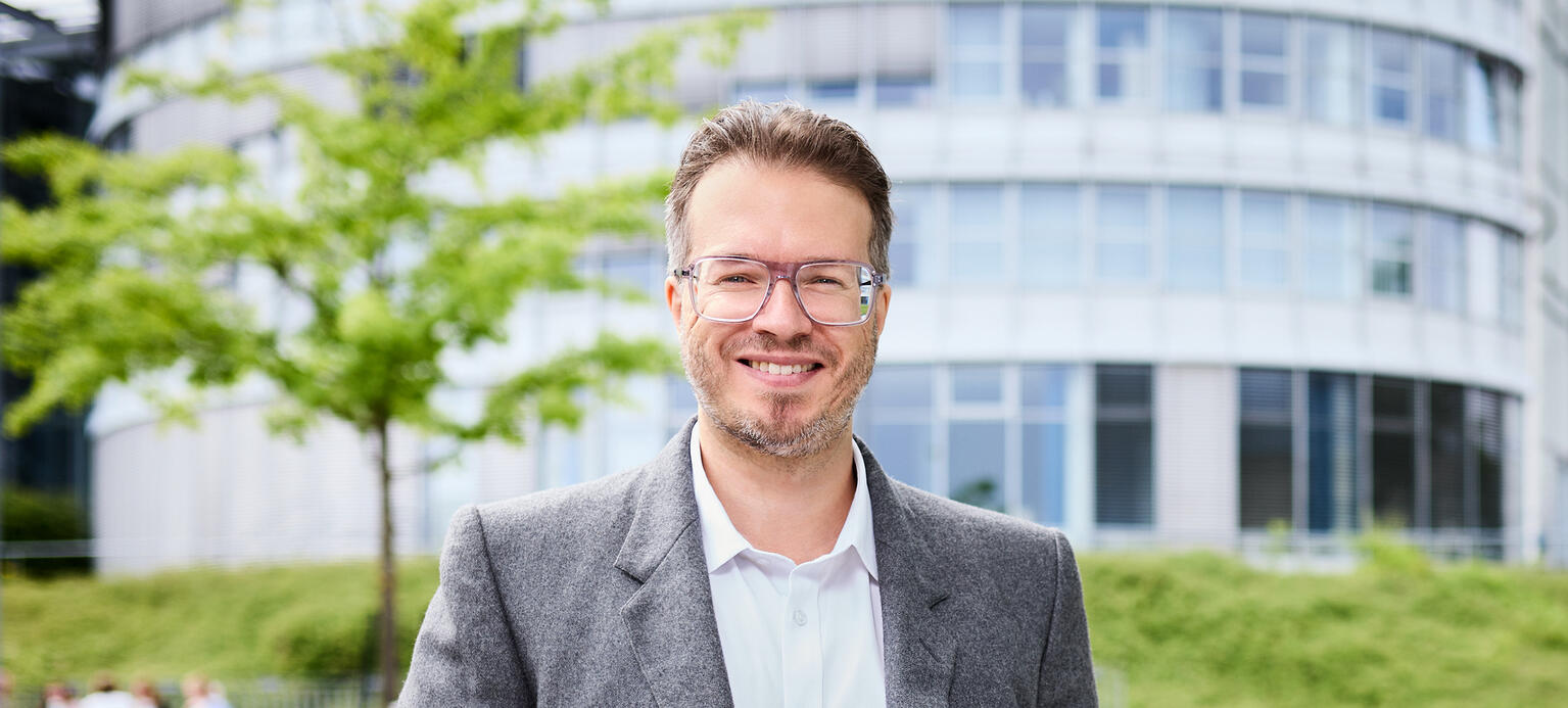 Das Foto zeigt Maximilian Waldmann, Preisträger 2025 vor einem Gebäude