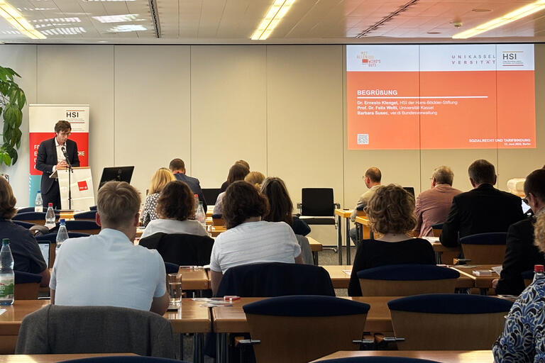 Zu sehen sind Bühne mit Vortragendem und Publikum bei der Pflegetagung des HSI 2025