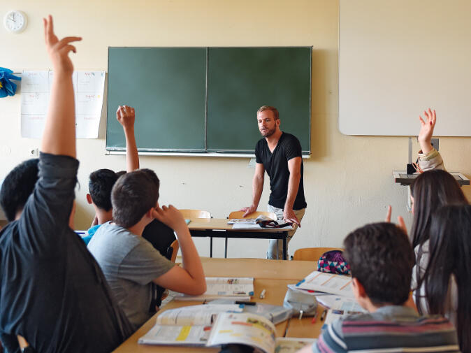 Klassenraum mit jugendlichen Schüler und Schülerinnen und Lehrer vor Tafel