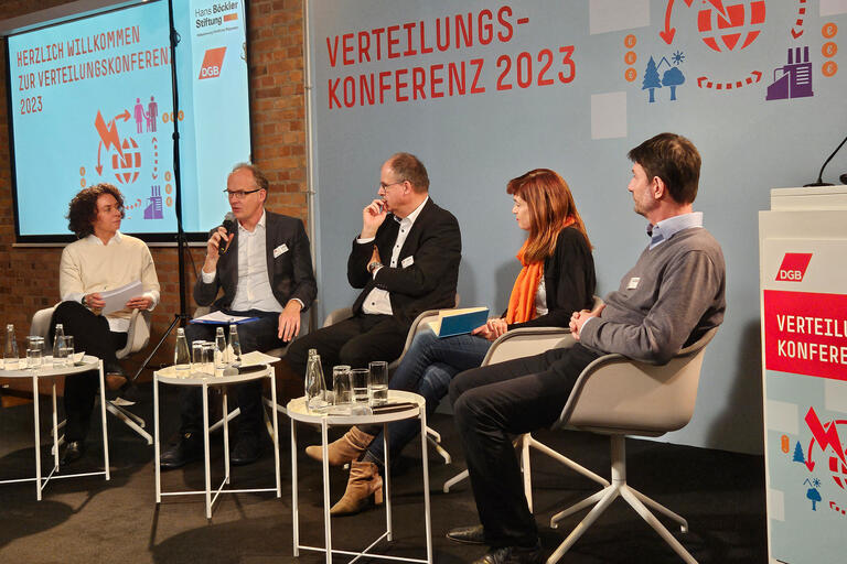 Mehrere Leute sitzen auf dem Podium und diskutieren