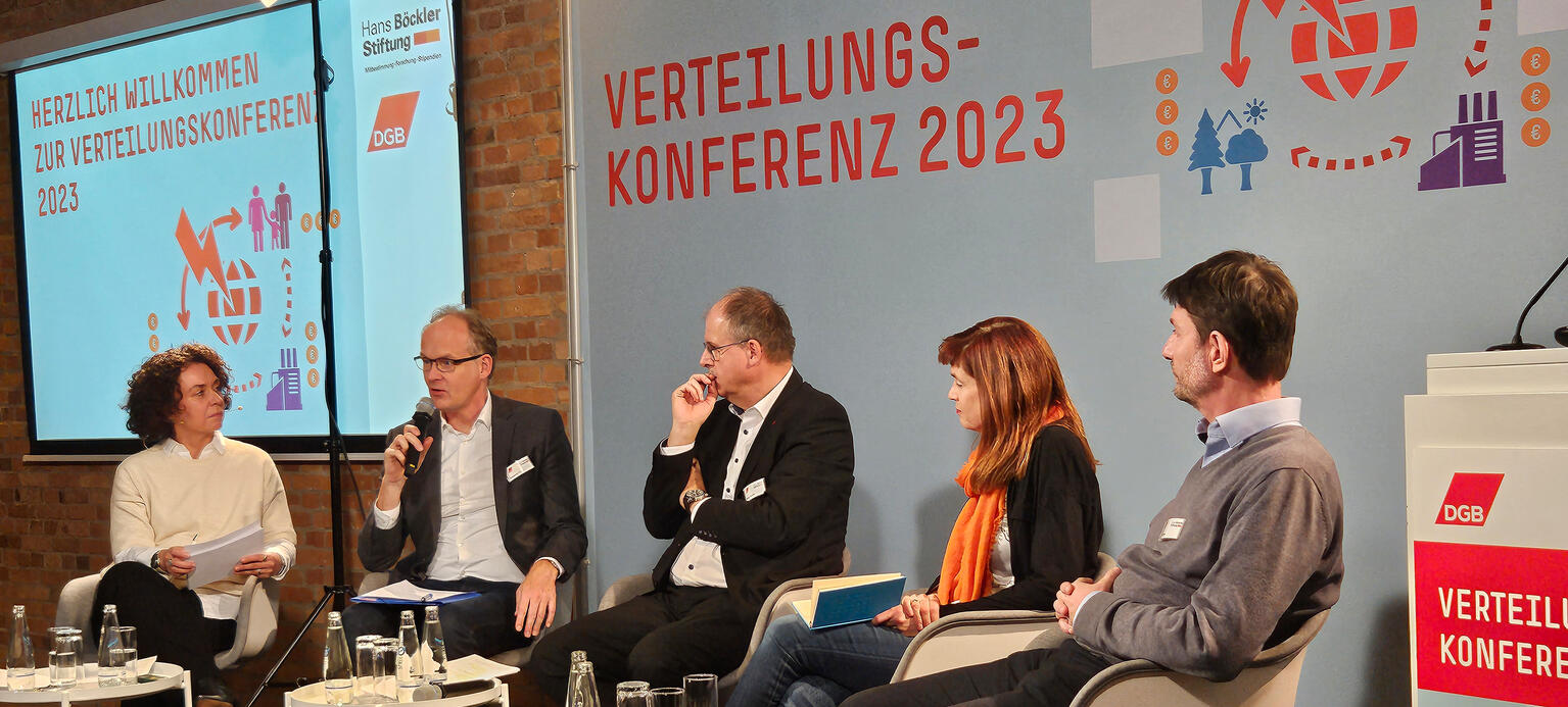 Auf dem Podium sitzen Leute und diskutieren