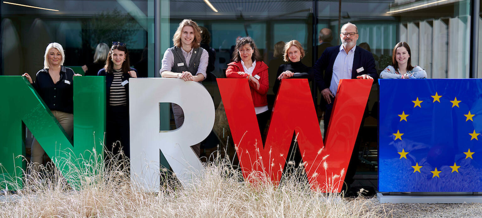 Große NRW-Buchstaben dahinter Vortragende der Workers-Voice Tagung 2024
