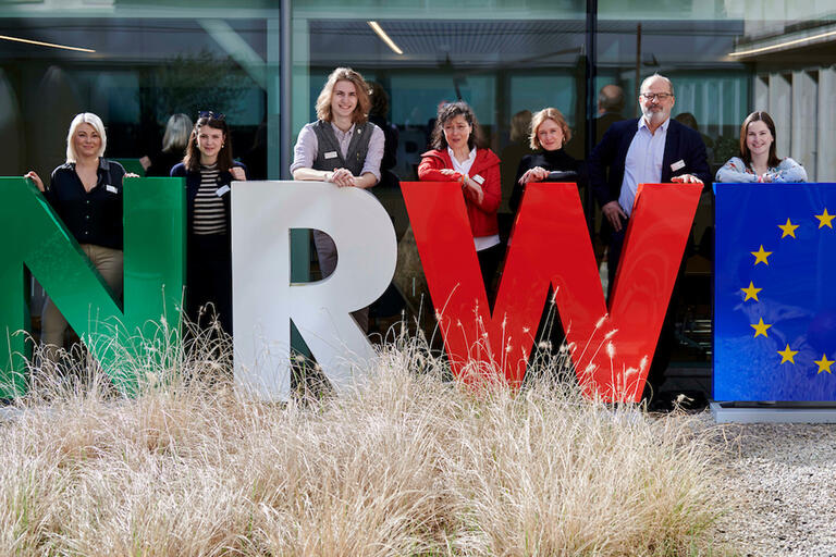 Große NRW-Buchstaben dahinter Vortragende der Workers-Voice Tagung 2024